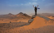 Backpacker tourist excitedly observes the landscape of the Ouzina desert in Morocco