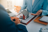 Fototapeta  - Real estate agent talked about the terms of the home purchase agreement and asked the customer to sign the documents to make the contract legally, Home sales and home insurance concept.