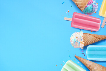Leinwandbilder - Assortment of colorful pastel ice cream cones and popsicle summer frozen desserts. Overhead view side border on a blue background. Copy space.