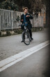 © qunica.com - Eco-friendly businessman in formal attire with a bike checking his watch while holding a smart phone in an urban setting.