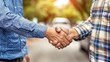 © Jevjenijs - A tight shot of two people handshaking, behind them a street backdrop blurred with a passing car