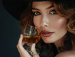 Femme élégante avec un chapeau noir et un verre de cognac à la main en train de déguster un alcool fort