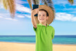 Little boy with hat and smiling making selfie by the smartphone tropical beach background
