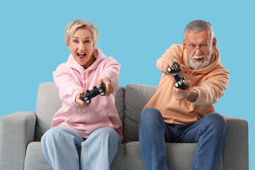 Canvas Print - Mature couple playing video game on sofa against blue background