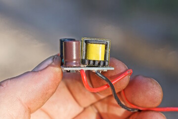 hand holds one small microcircuit with electrical parts and wires