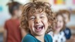 Close up of elementary student with curly hair laugh while looking at camera. Happy children or kid with casual shirt sitting and surrounded with student at school with blurring background. AIG42.