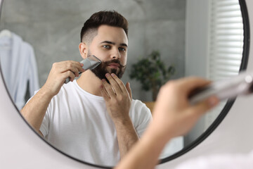 Poster - Handsome young man trimming beard near mirror in bathroom