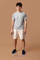 Canvas Print - Sporty guy with jumping rope on beige background