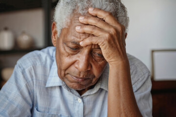 Wall Mural - African man pensioner is sitting with his hand on his head. He looks sad and is frowning, headache