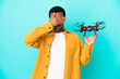 African American handsome man holding a drone over isolated blue background covering eyes by hands. Do not want to see something