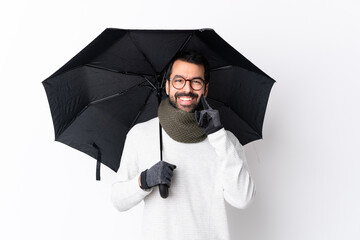 Wall Mural - Caucasian handsome man with beard holding an umbrella over isolated white wall smiling with a happy and pleasant expression