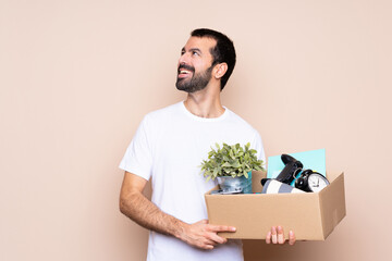 Wall Mural - Man holding a box and moving in new home over isolated background happy and smiling