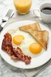 Delicious breakfast with sunny side up eggs served on white marble table, closeup