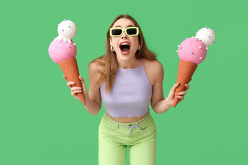 Sticker - Surprised young woman holding toy ice creams on green background