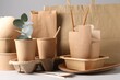 Eco friendly food packaging. Paper containers, tableware, bag and eucalyptus branch on white table