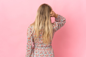 Poster - Young blonde woman isolated on pink background in back position and thinking