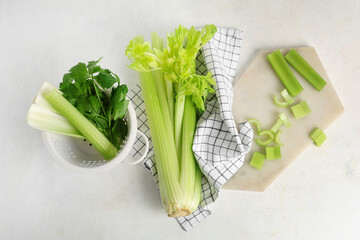 Wall Mural - Board and colander with fresh green celery on white background