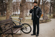 © qunica.com - A contemporary businessman enjoying a moment of solitude in the park, standing next to his bicycle.