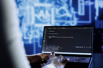 Certified admin updates neural networks made up of interconnected nodes, writing intricate binary code scripts on laptop. Proficient specialist uses programming to upgrade AI simulation model