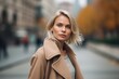 © MediaRaw - A blonde woman wearing a tan coat stands on a city street