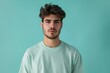 © MediaRaw - A man with a beard and a green shirt is standing in front of a blue wall