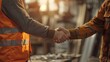 © DWN Media - Close up of two men shaking hands in the background of an industrial warehouse.