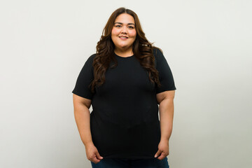 Beautiful plus-size woman posing with a black t-shirt for a mockup in a studio with white background