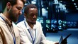 © DC Studio - IT team running data center components diagnostic tests to determine and patch software issues. Workers using laptop and tablet to mend critical systems, checking for defects, close up