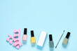 Nail polishes, toe separators, buffer and cuticle pusher on light blue background, flat lay. Space for text