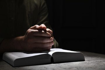 Wall Mural - Religion. Christian man praying over Bible at table, closeup. Space for text