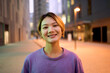 © CarlosBarquero - Portrait beautiful Asian nice young woman smiling with friendly expression looking joyful at camera outdoor. Generation z pretty Chinese female with blonde hair posing cheerful in city center at dusk
