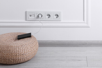 Wall Mural - Power bank plugged into electric socket on white wall, space for text