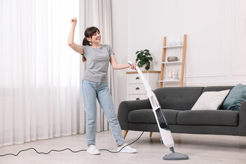 Poster - Happy young housewife cleaning floor with steam mop at home