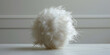 A white fluffy ball of fur, adorned with feathers, is presented on a white surface, showcasing filthy sculptures, layered fibers, recycled materials, and blurred imagery.
