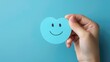 a hand holding a blue paper cut-out of a happy smiley face, symbolizing positive thinking. Ai Generated