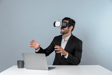 Skilled business man looking at data analysis while sitting at table with laptop and wearing VR glasses. Project manager working by using virtual reality system or connecting at metaverse. Deviation.