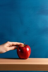 Poster - Red apple on wooden table against blue background