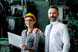 © Stella - Young beautiful woman industrial engineer worker with helmet and safety glasses using laptop computer during discussing with senior businessman manager, people work at manufacturing industry factory