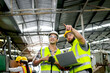 © Stella - Industrial foreman and worker with helmet and safety vest using laptop computer during discussing together at manufacturing industry factory. Engineer inspecting workplace and checking process.
