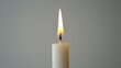  A candle with a white base and a yellow candle inserted vertically through its center, topped by another single candle