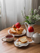 Cozy morning - breakfast served with fresh brioche rolls, tea, a bouquet of flowers on a round wooden table
