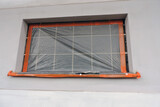 Fototapeta Zwierzęta - A glass block window and a windowsill covered with a protective film, an exterior wall which is covered with prime and partially rendered

