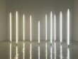 Array of vertical light tubes in a minimalist art gallery creating a serene atmosphere.