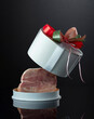 Opened gift box with ham on a black background.
