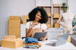 © Nuttapong punna - Startup small business SME, Entrepreneur owner woman using smartphone or tablet taking receive and checking online purchase shopping order