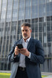 © Stock 4 You - Mature hispanic senior business man using smartphone cellphone financial application. Focused serious latin middle age male entrepreneur businessman holding mobile cell phone for trading. Vertical
