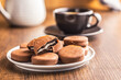 Close-Up View of Chocolate-Coated Sandwich Cookies on wooden table.