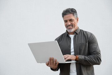 Mature 40s Indian happy man using wireless pc for business solutions, isolated on white background. Middle age freelance entrepreneur, latin hispanic businessman holding laptop computer, working busy