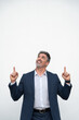 © Stock 4 You - Successful happy businessman point fingers up standing on white background. Isolated, vertical. Smiling mid age mature businessman in formal suit, pointing hands at copy space for promo advertising
