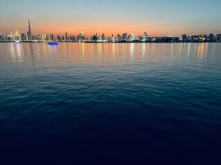 Wall Mural - city river at the sunset time, down town silhouette at the background, orange sky, water reflection 